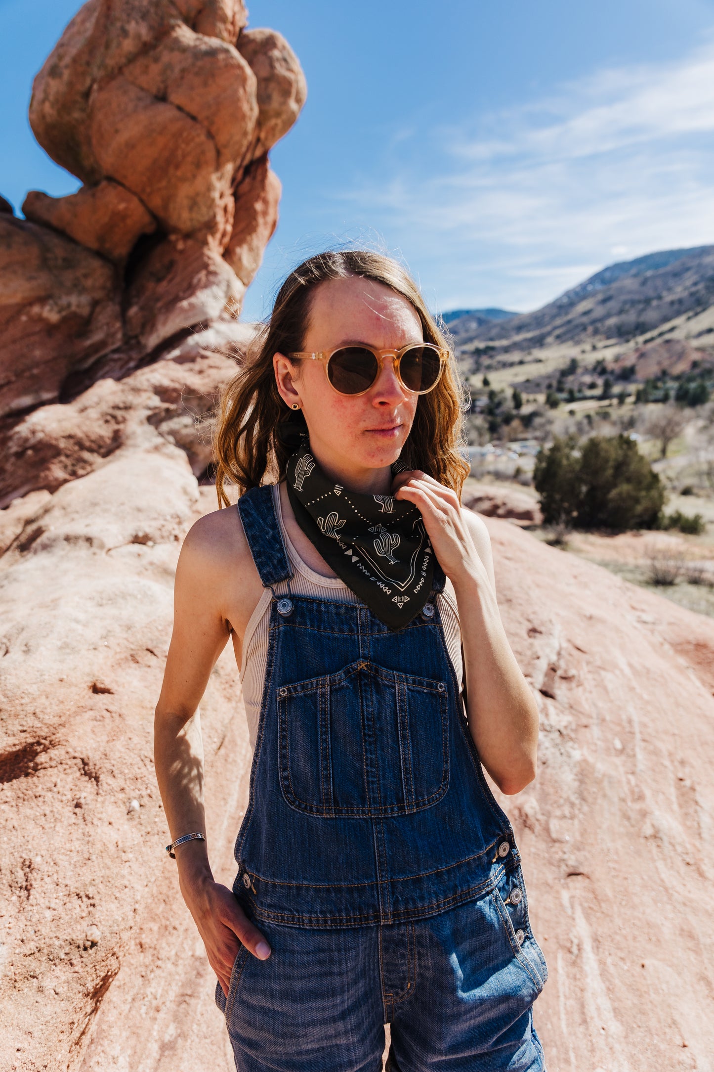 a woman in sunglasses is standing on a rock